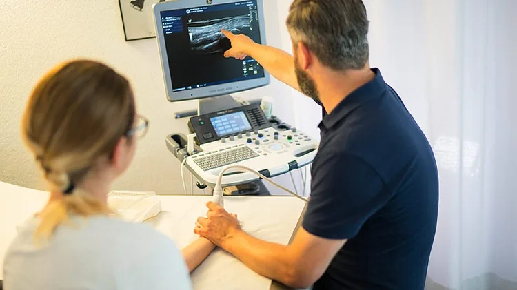 Ein Arzt untersucht eine Hand einer Patientin.